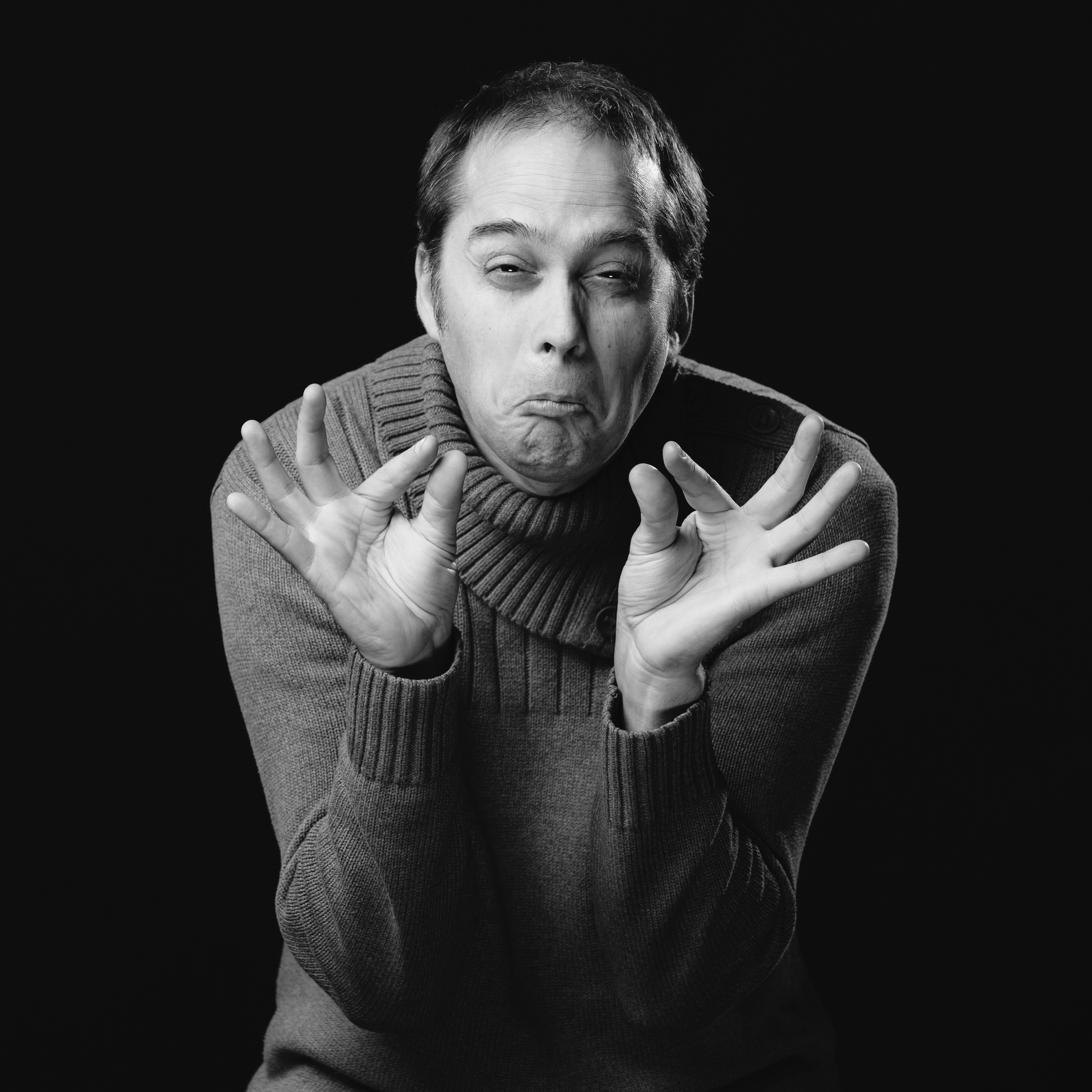 Mann i sorthvitt med hendene foran seg