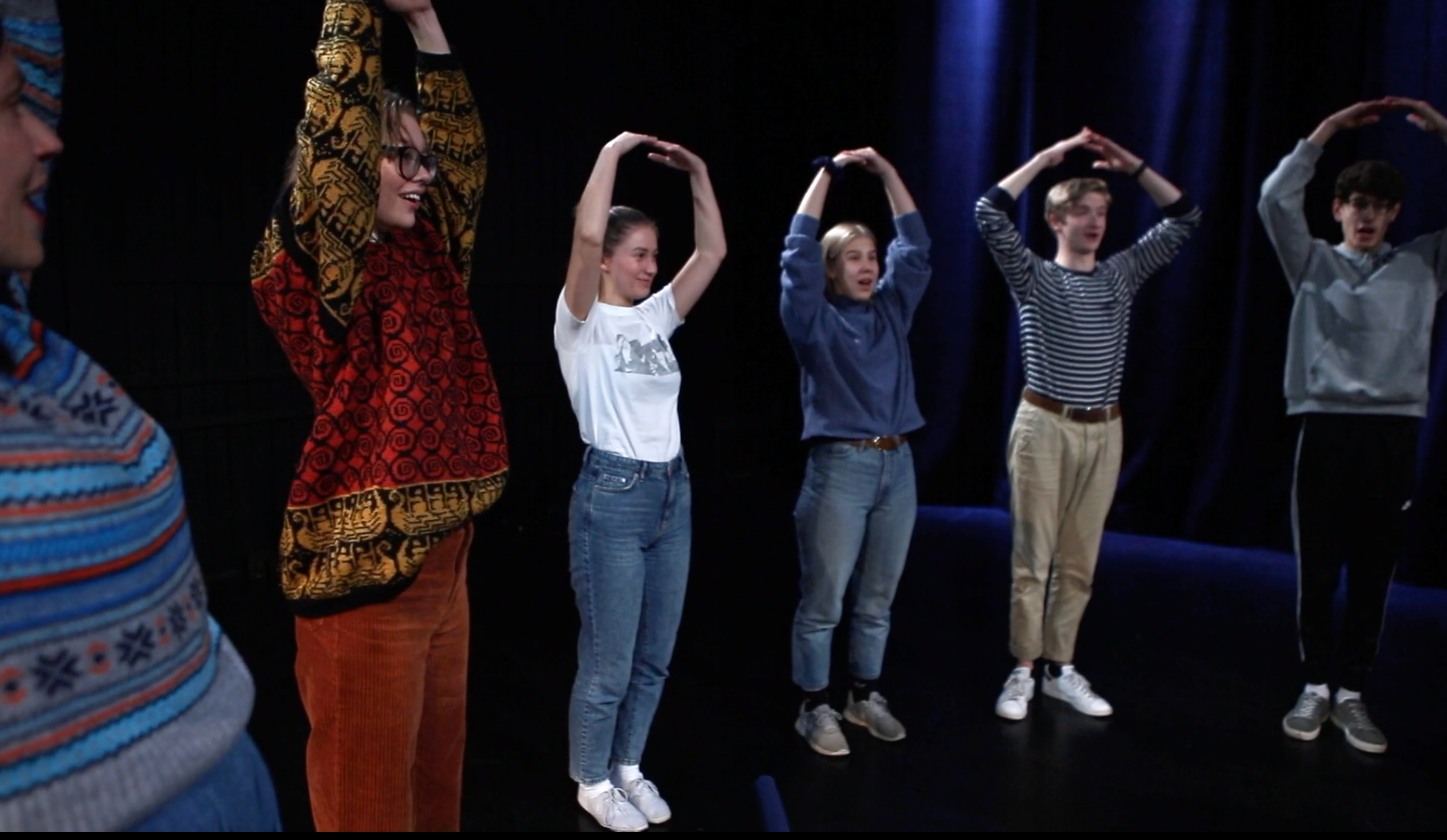 Vi ser ungdom som står med hender over hodet