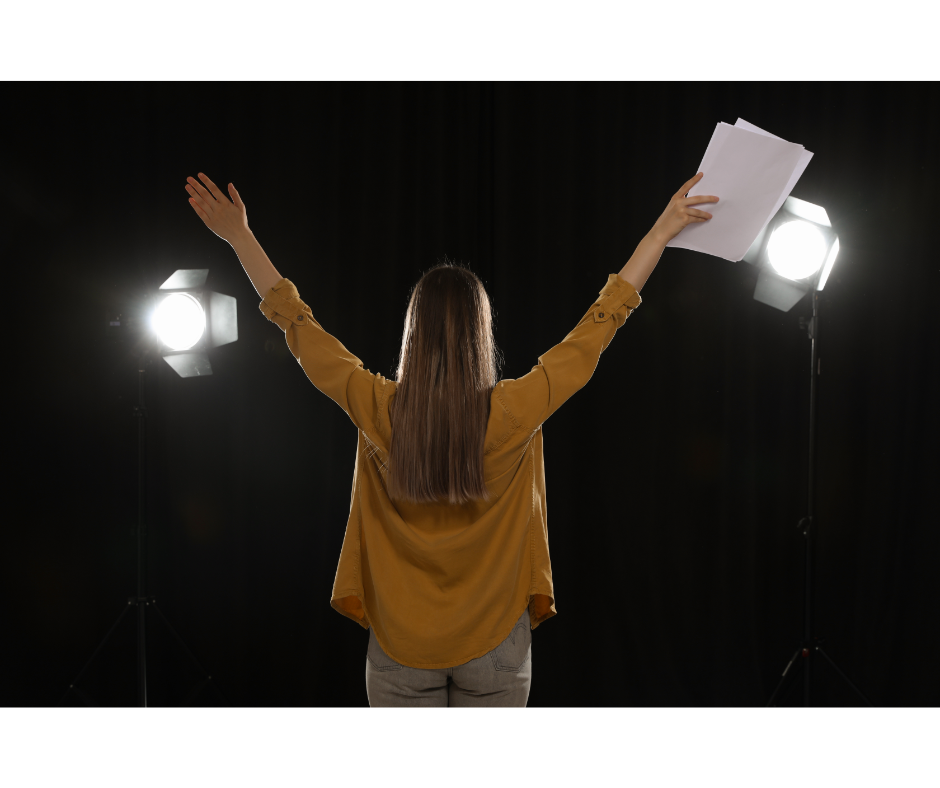 jente på scenen med armene strekt opp og en tekst i den ene hånden