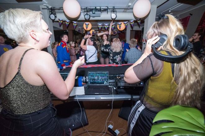 bilde av DJ som står foran en dansende mengde