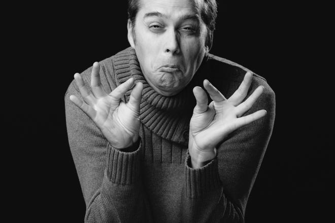 Mann i sorthvitt med hendene foran seg